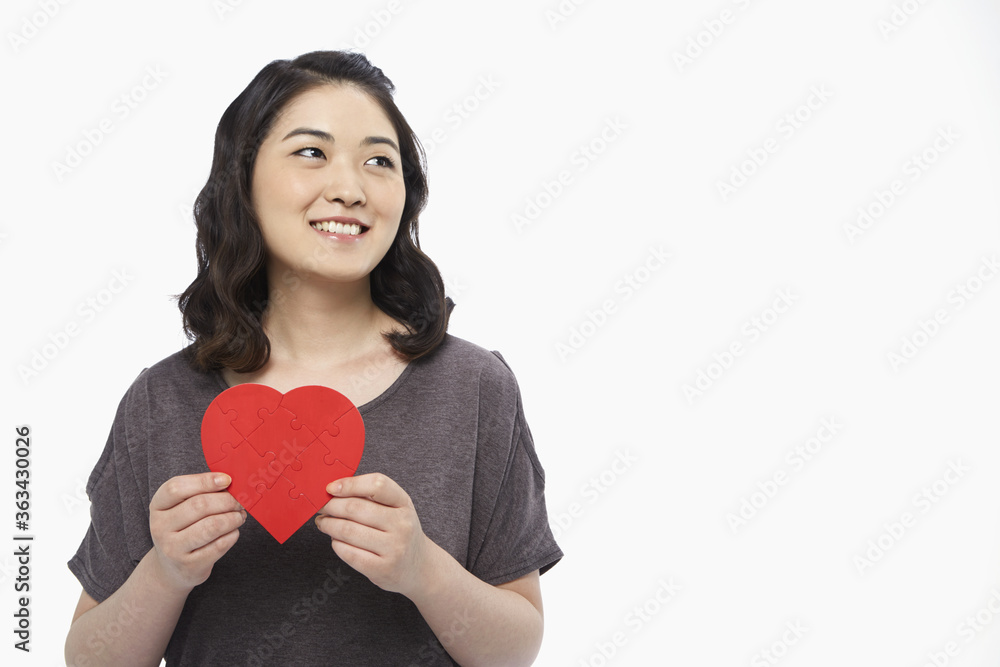Cheerful woman holding up a red heart shape Cheerful woman holding up a red heart shape