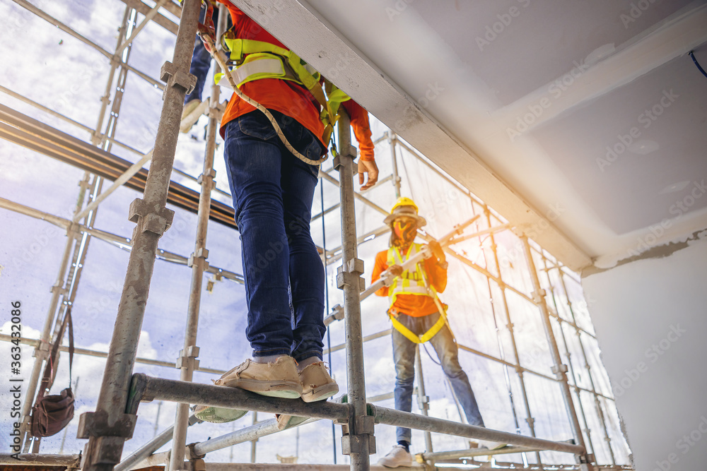 Construction workers in safety uniform install reinforced steel scaffolding at outdoor construction site. Construction workers in safety uniform install reinforced steel scaffolding at outdoor construction site.