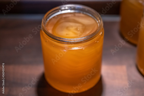 Golden yellow honey in glass jar on wooden board Closeup Copy space comp frame empty textspace