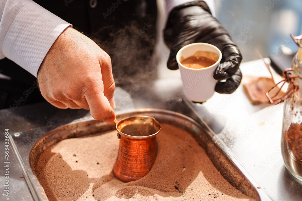 male hand preparing Turkish coffee in burning sand at Souq Waqif