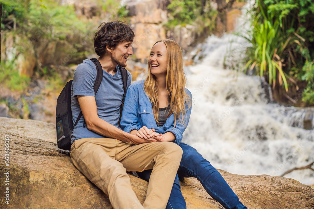 Couple of tourists with a backpack on the background of a waterfall Couple of tourists with a backpack on the background of a waterfall