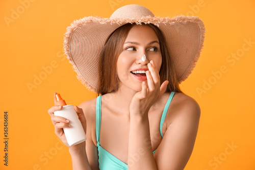 Canvastavla Young woman applying sunscreen cream against color background
