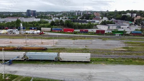 Wallpaper Mural Drone footage of a derelict train yard and a passing train, with buildings and traffic visible in the background. Torontodigital.ca