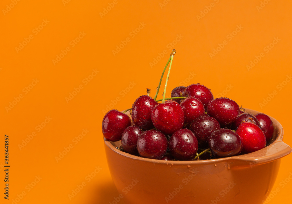 Cherries with water drops in bowl on terracota background. Fruit bowl. Delicious food. Copy space. High quality close up photo. Cherries with water drops in bowl on terracota background. Fruit bowl. Delicious food. Copy space. High quality close up photo.