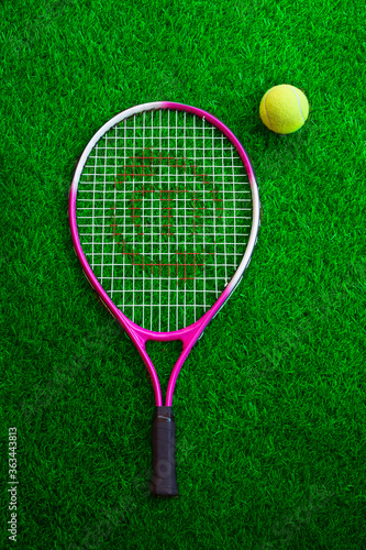 dual colour tennis racket and ball on resting on grass