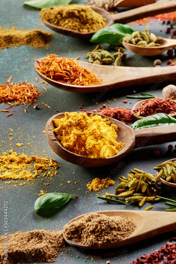 Various spice and dried herbs on dark green background.