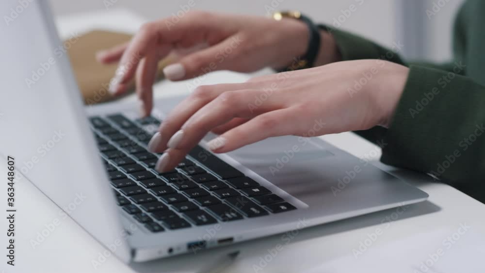 Close-up handheld shot of unrecognizable young females hands typing something on laptop in modern office Close-up handheld shot of unrecognizable young females hands typing something on laptop in modern office