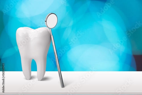 Human s white tooth and dentist mirror on desk