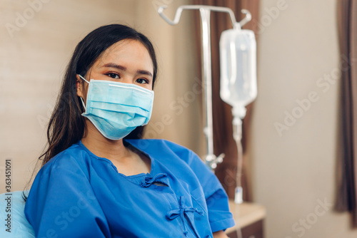 Portrait of asian woman patient sitting on bed wearing protective mask with health medical care express trust and Insurance concept in room at hospital