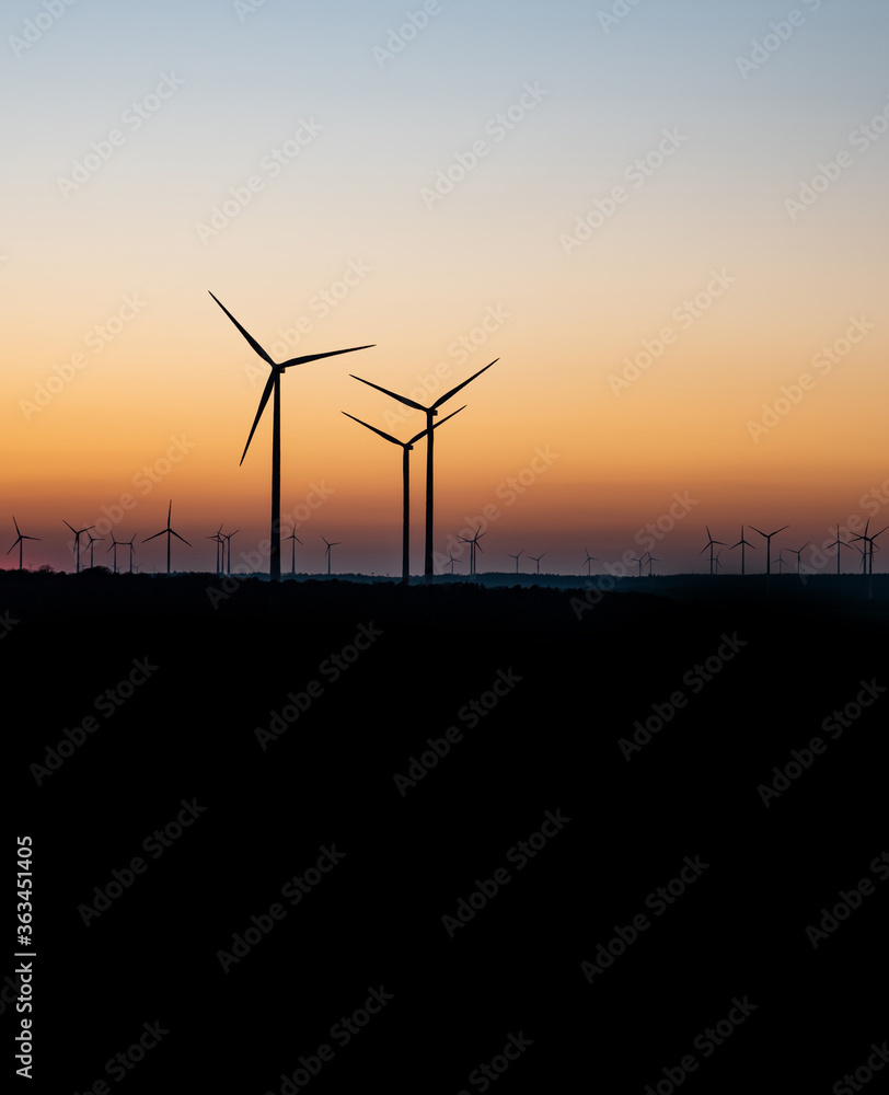 Obraz premium Black Silhouette of windturbines energy generator on amazing sunset at a wind farm in germany