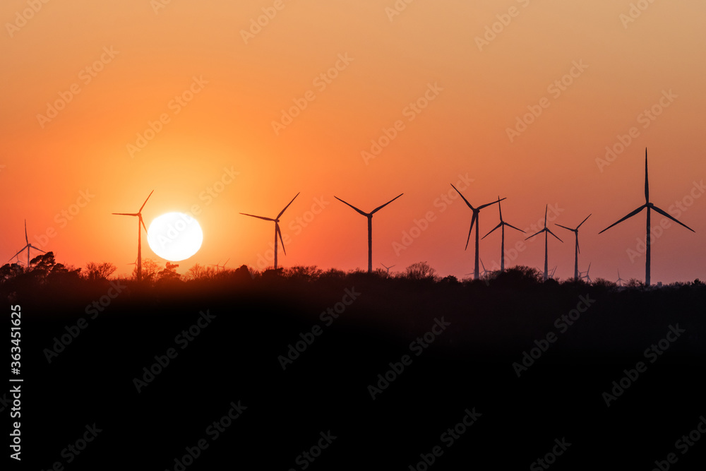 Fototapeta premium Black Silhouette of windturbines energy generator on amazing sunset at a wind farm in germany
