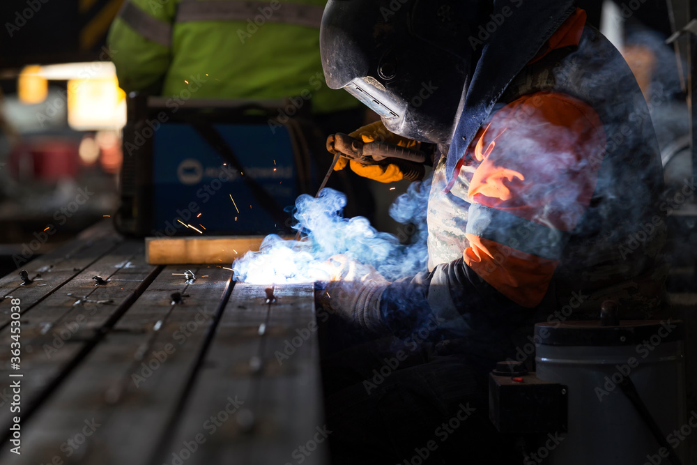 The welder is welding with shielded metal arc welding (SMAW). It is also known as manual metal