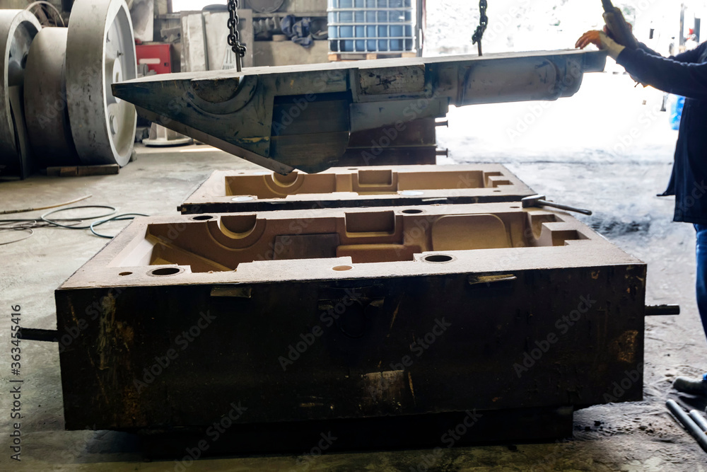 The worker is preparing sand mold for steel casting. The mold cavities
