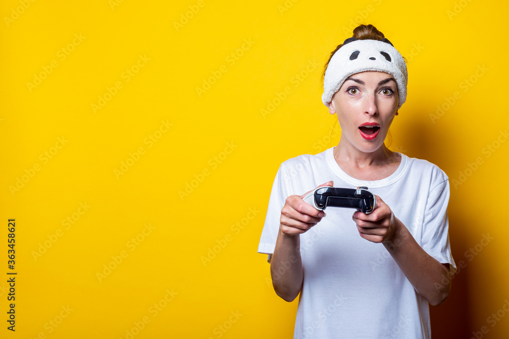 Surprised young girl in a white T-shirt with a joystick in hands on a yellow background. Surprised young girl in a white T-shirt with a joystick in hands on a yellow background.