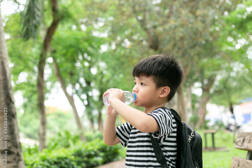 Cute little boy drinking mineral water from the plastic bottle in the park Cute little boy drinking mineral water from the plastic bottle in the park