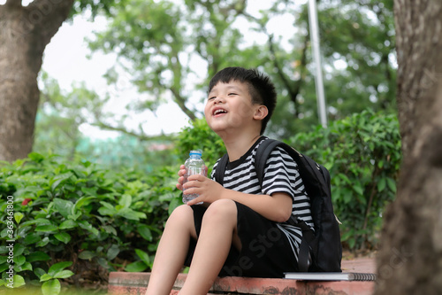 Cute little boy drinking mineral water from the plastic bottle in the park © Keopaserth