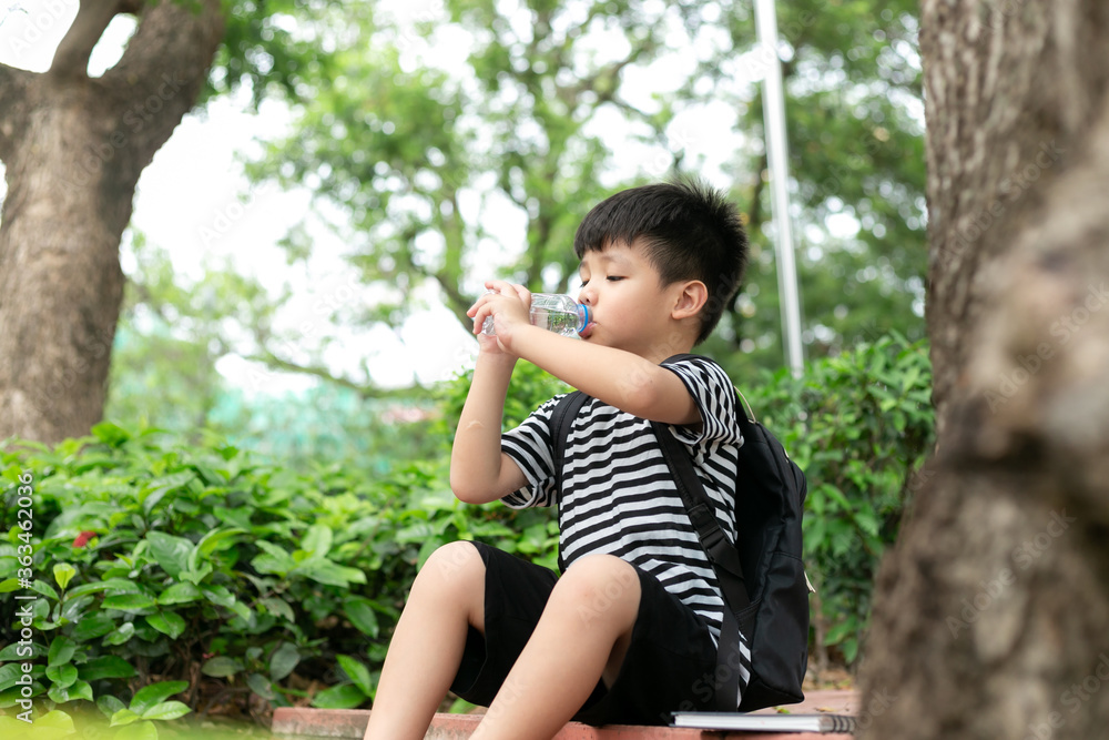 Cute little boy drinking mineral water from the plastic bottle in the park Cute little boy drinking mineral water from the plastic bottle in the park