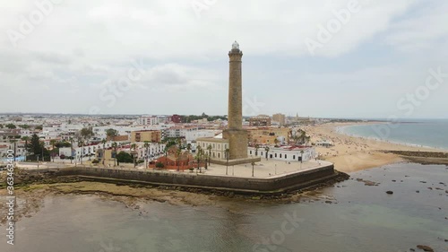 The high lighthouse of Chipiona on the Atlantic in Andalusia. The drone flies a semicircle with a view of the city and the coastal landscape in the north.