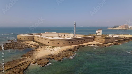 The lighthouse San Sebastian on a small fortress island in the Atlantic in front of the Spanish port city of Cadiz. A sea side aerial view in summer with a blue sky.