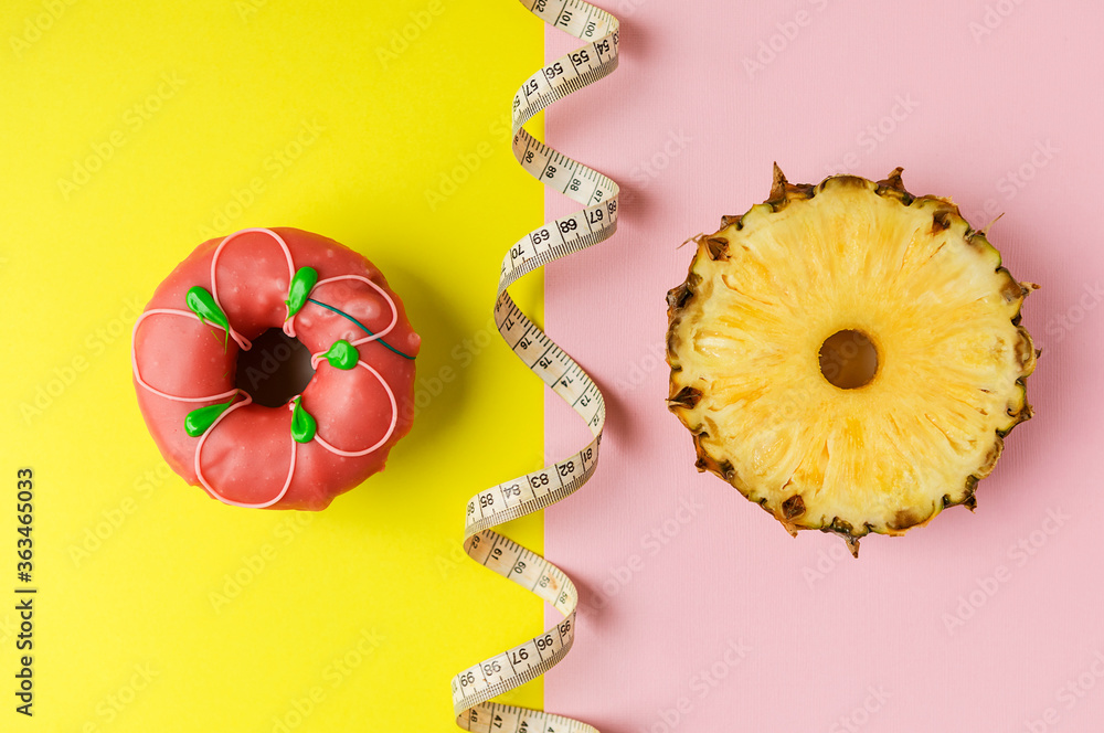 a doughnut and a circle of fresh pineapple on a yellow-pink background. the concept of choosing the right food. a doughnut and a circle of fresh pineapple on a yellow-pink background. the concept of choosing the right food.