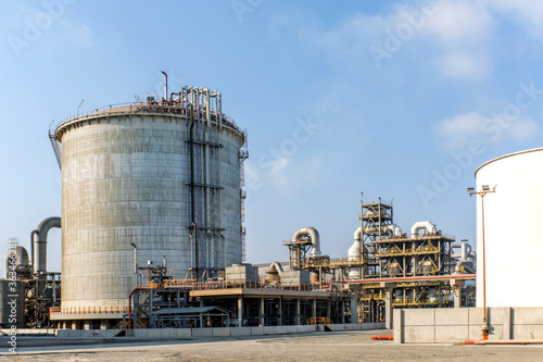 View of the double walled, vertical, cylindrical ammonia storage tank and process piping in the industrial plant. In Fertilizers Industries surplus ammonia is stored in a large capacity tank.
