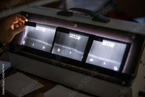 The inspector is reviewing to the radiography film of the pipe welds. The writes on the films are an penetrameter (European Standard). It is a quality indicators.