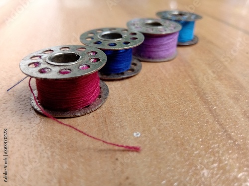 Four bobbins are placed in a line.