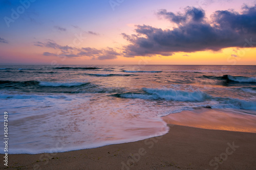 dawn at the beach of a black sea. gorgeous sky above the water surface. tide washing the shore