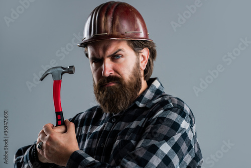 confident construction engineer. professional architect. repair and building. use hammer tool. serious male worker wear hard hat. brutal builder in helmet. bearded repairman photo