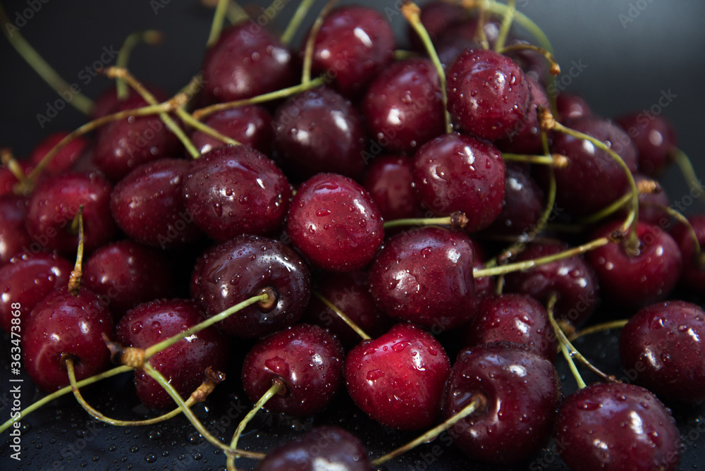 Red fresh cherries on a black background. Drop of water. Close up. The concept of freshness. Red fresh cherries on a black background. Drop of water. Close up. The concept of freshness.