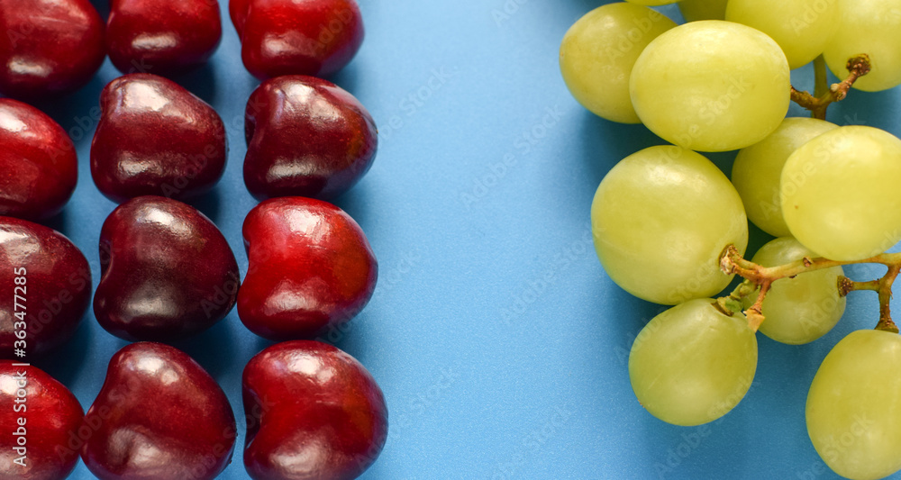 Cherry and green grapes on a blue background. Cherry and green grapes on a blue background.