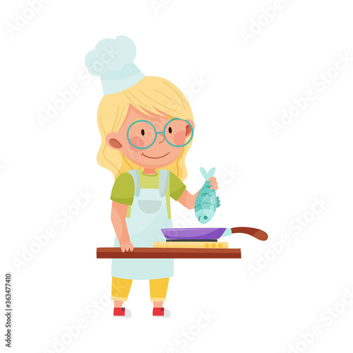 Cute Girl Character in Hat and Apron Standing at Kitchen and Frying Fish in Frying Pan Vector Illustration