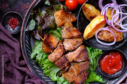 Skewers of Meat with sauce on wooden cutting board, ready to be served as summer party meal, view from above.