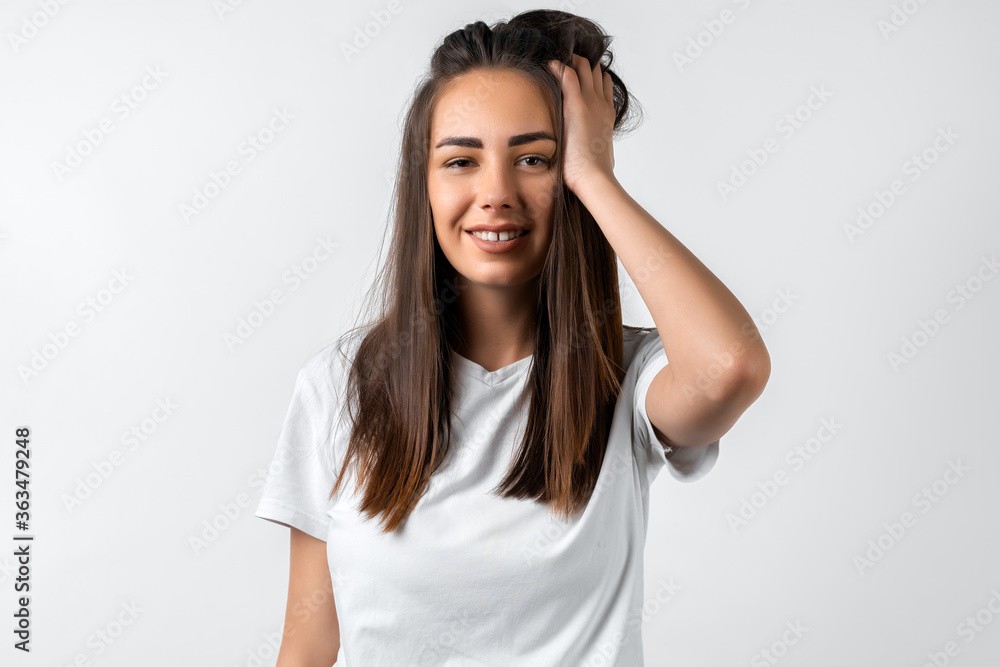 Pretty carefree modern girl with long chestnut hair holding to her head or touching hair. Isolated on white background. Emotions, expressions, hairstyle and people concept. Pretty carefree modern girl with long chestnut hair holding to her head or touching hair. Isolated on white background. Emotions, expressions, hairstyle and people concept.