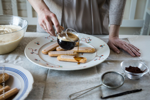 Step by step tiramisu. Pouring coffee with cognac on ladyfingers.