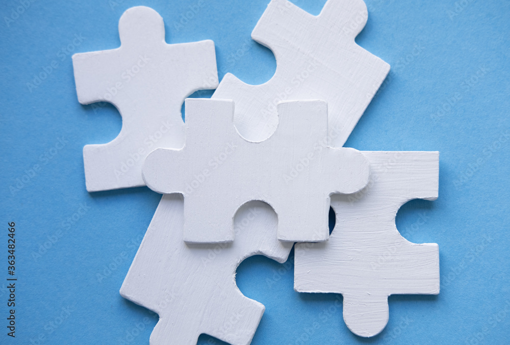 White Jigsaw Puzzle pieces on blue background top view. Concept for Unite. Symbol of association and connection, business strategy, completing, team support and help concept. Space for text on puzzle White Jigsaw Puzzle pieces on blue background top view. Concept for Unite. Symbol of association and connection, business strategy, completing, team support and help concept. Space for text on puzzle