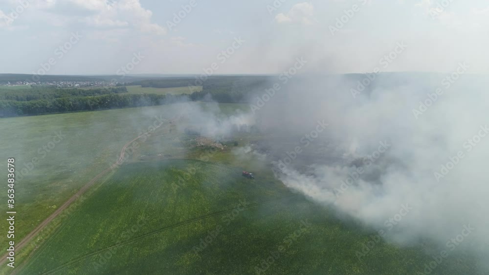 07. Aerial view of Fire in the field. Burning grass and trash. Next to a tractor with a water barrel, a man puts out a fire. Near the forest. Summer sunny day
07. Aerial view of Fire in the field. Burning grass and trash. Next to a tractor with a water barrel, a man puts out a fire. Near the forest. Summer sunny day