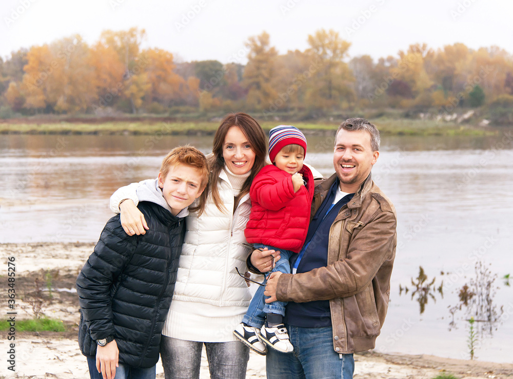 Happy family is standing near the river in the autumn day. Happy family is standing near the river in the autumn day.
