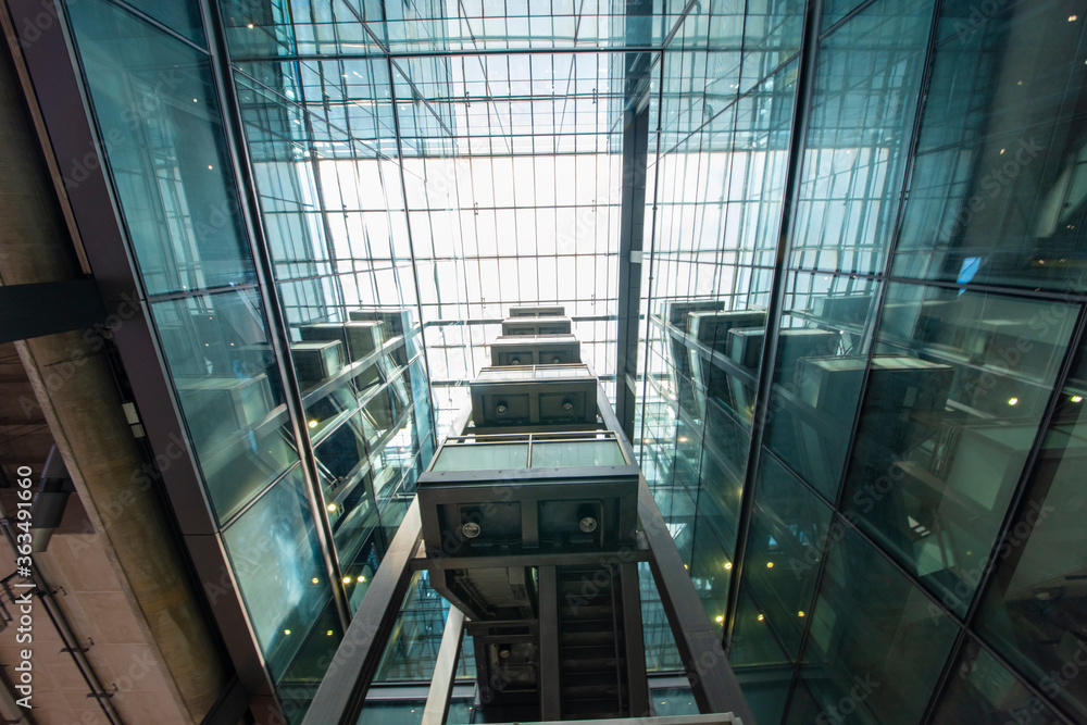 Obraz premium Modern glass elevator and pedestrian stairway entrances.