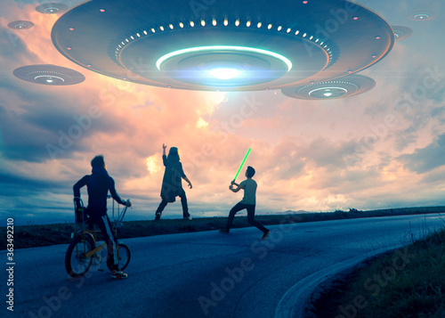 Fotografía Alien invasion of a big flying saucer  in a beautiful sunset sky while children