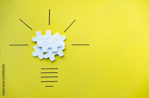 Light bulb over yellow background in vision and idea conceptual image. Conceptual image of creativity and idea. Jigsaw Puzzle pieces on yellow background. Symbol of business strategy and idea.