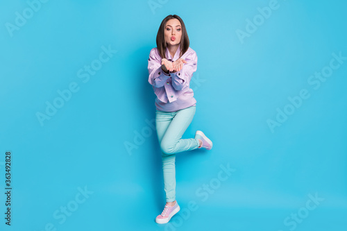 Full length body size view of her she nice attractive pretty lovable charming sweet teen girl having fun jumping sending air kiss isolated on bright vivid shine vibrant blue color background