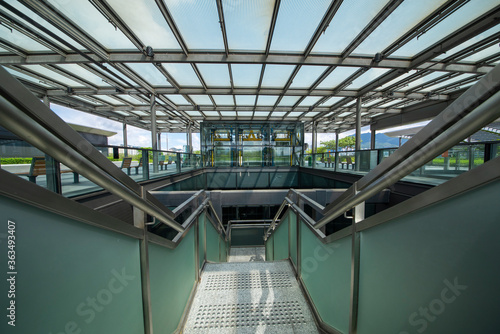 Modern glass elevator and pedestrian stairway entrances.