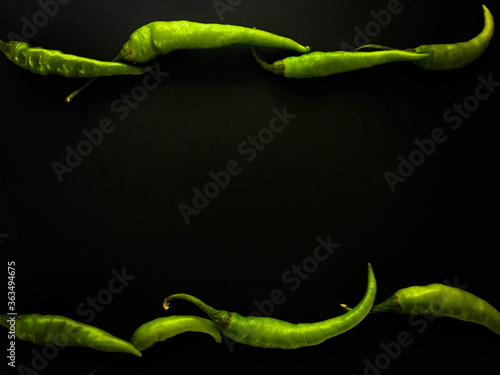 Natural green chillies on a dark background. Top view with food background, black stone table, copy space.