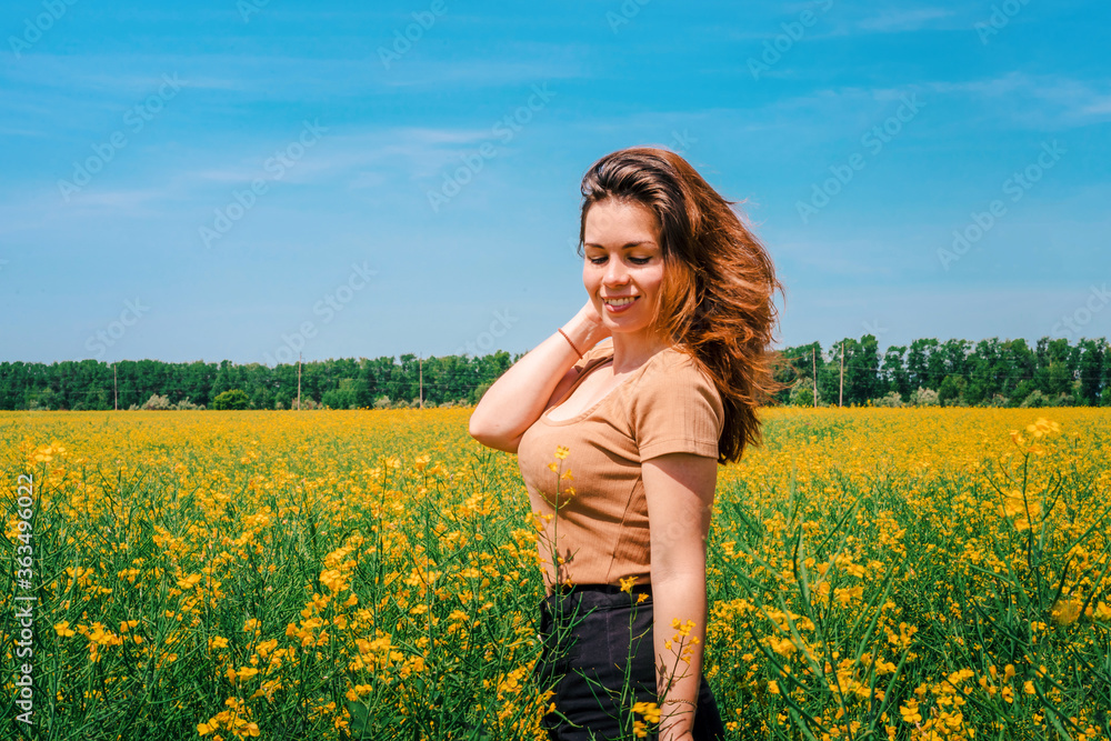 Portrait of a smiling young girl with long hair in a thick rapeseed field with a blue clear sky, place for text, copyspace Portrait of a smiling young girl with long hair in a thick rapeseed field with a blue clear sky, place for text, copyspace