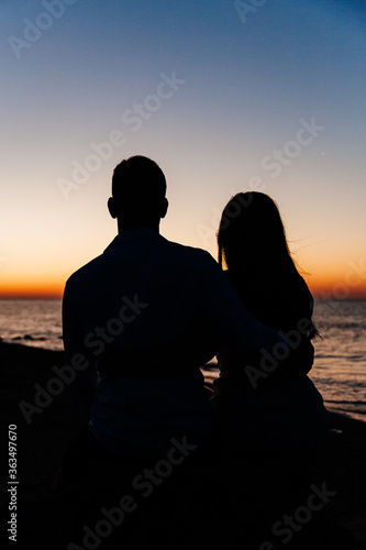 Loving couple in white clothes during a honeymoon at sea walk on the sand at a photoshoot Love Story, ocean coast, beach, silhouette