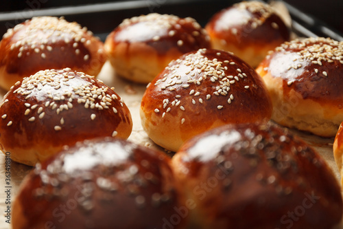 Fresh hot sweet buns with sesame seeds from the oven, homemade bakery.