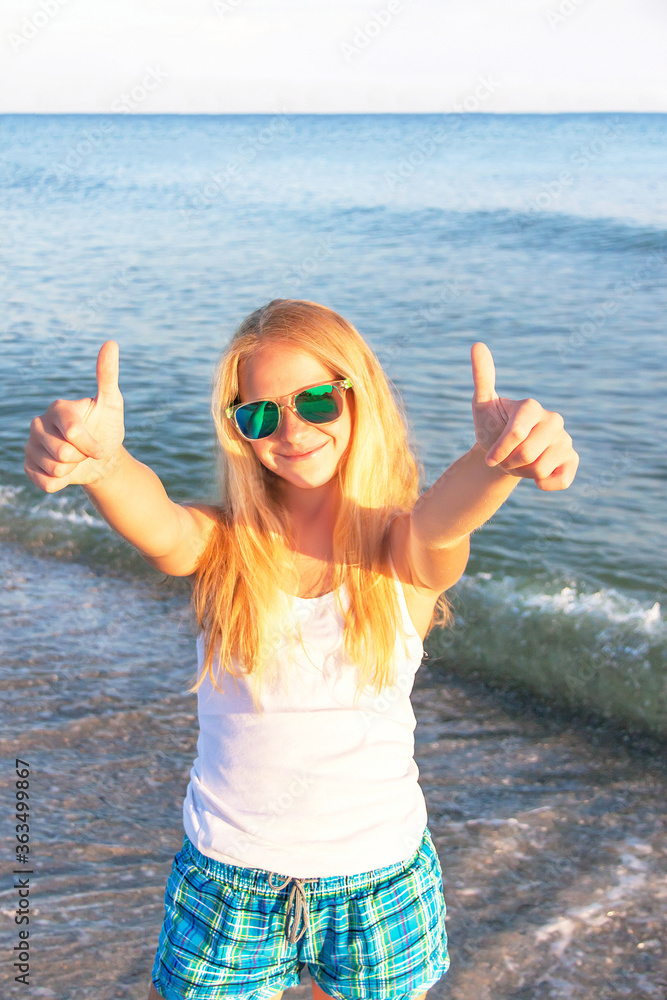 Teen girl showing thumbs up on the sea background. Teen girl showing thumbs up on the sea background.