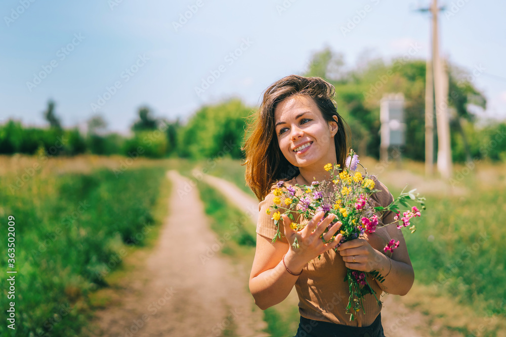 Portrait of a beautiful girl with long hair on a country road in summer nature holding a bouquet of colorful flowers, a banner for beauty products or ecology, a place for text Portrait of a beautiful girl with long hair on a country road in summer nature holding a bouquet of colorful flowers, a banner for beauty products or ecology, a place for text