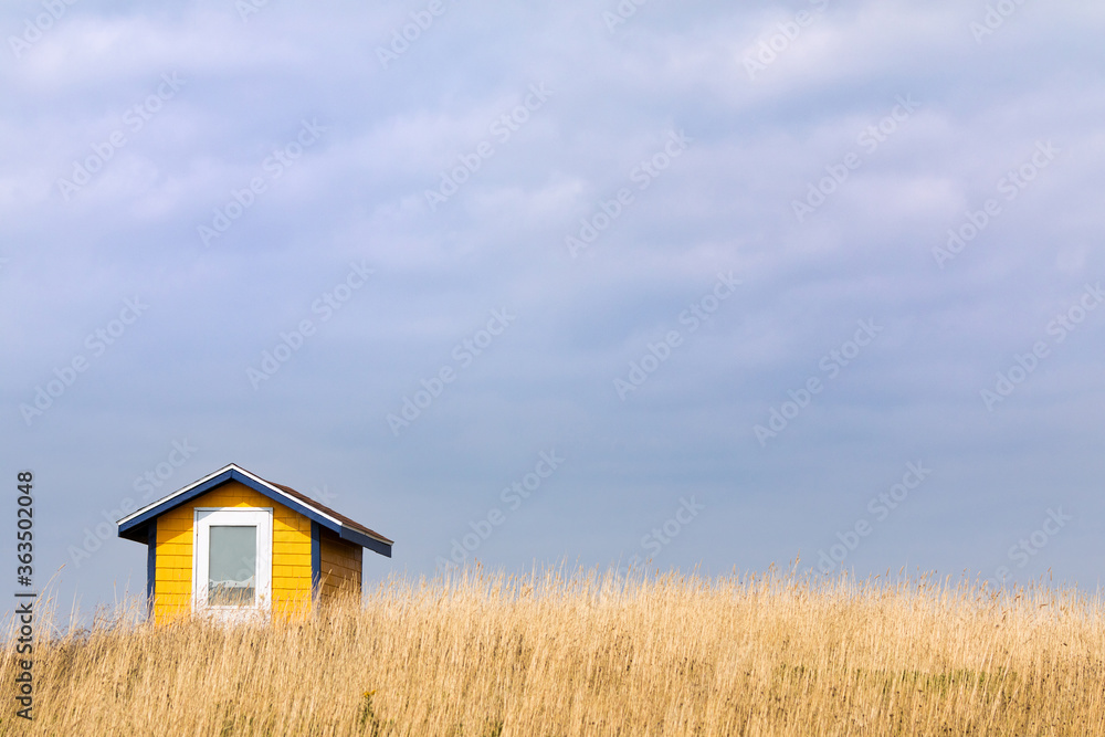 Yellow hut in a field of grass with summer blue sky background